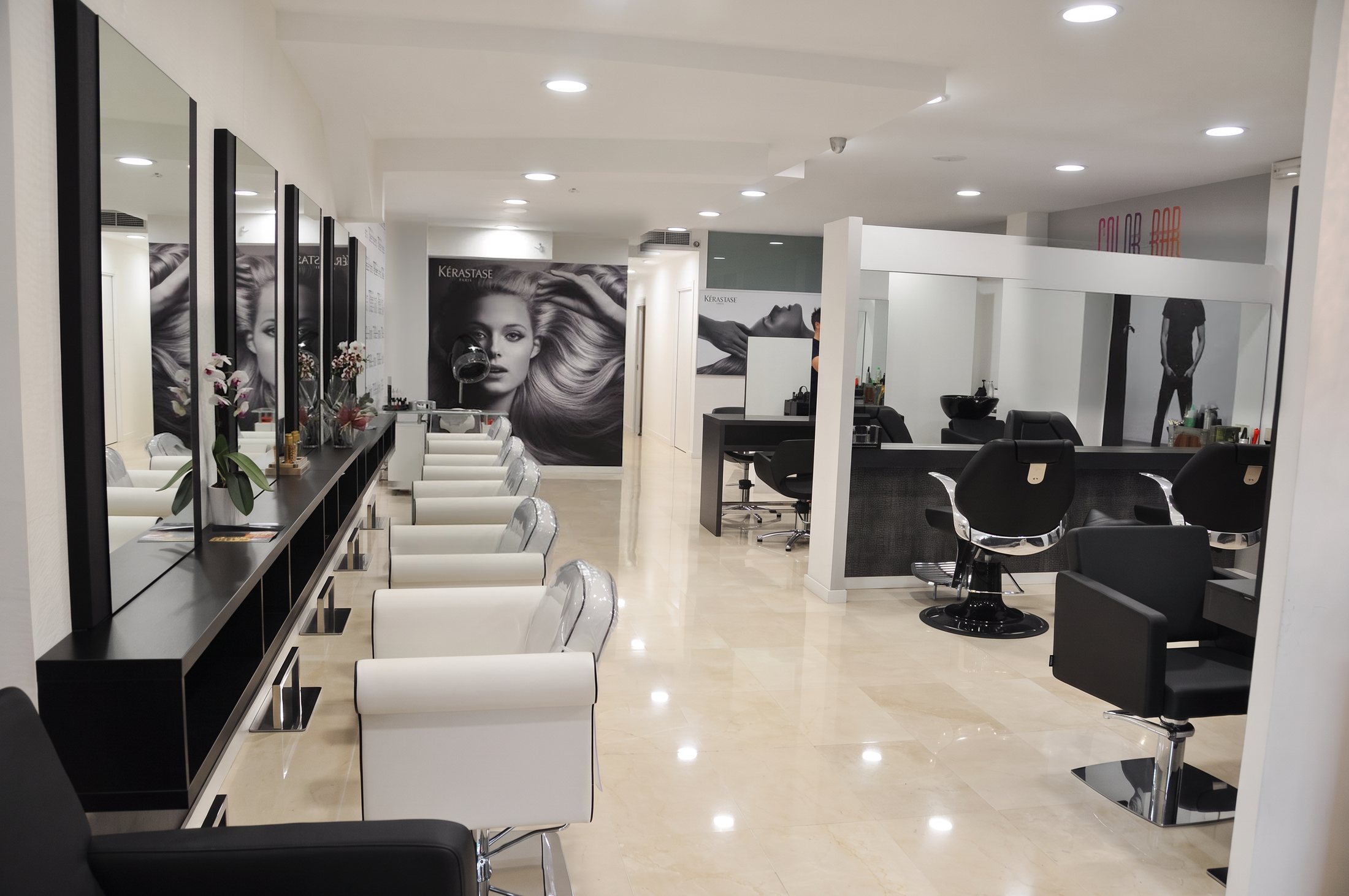 Fila de tocadores con sillones blancos y zona de barbería al fondo