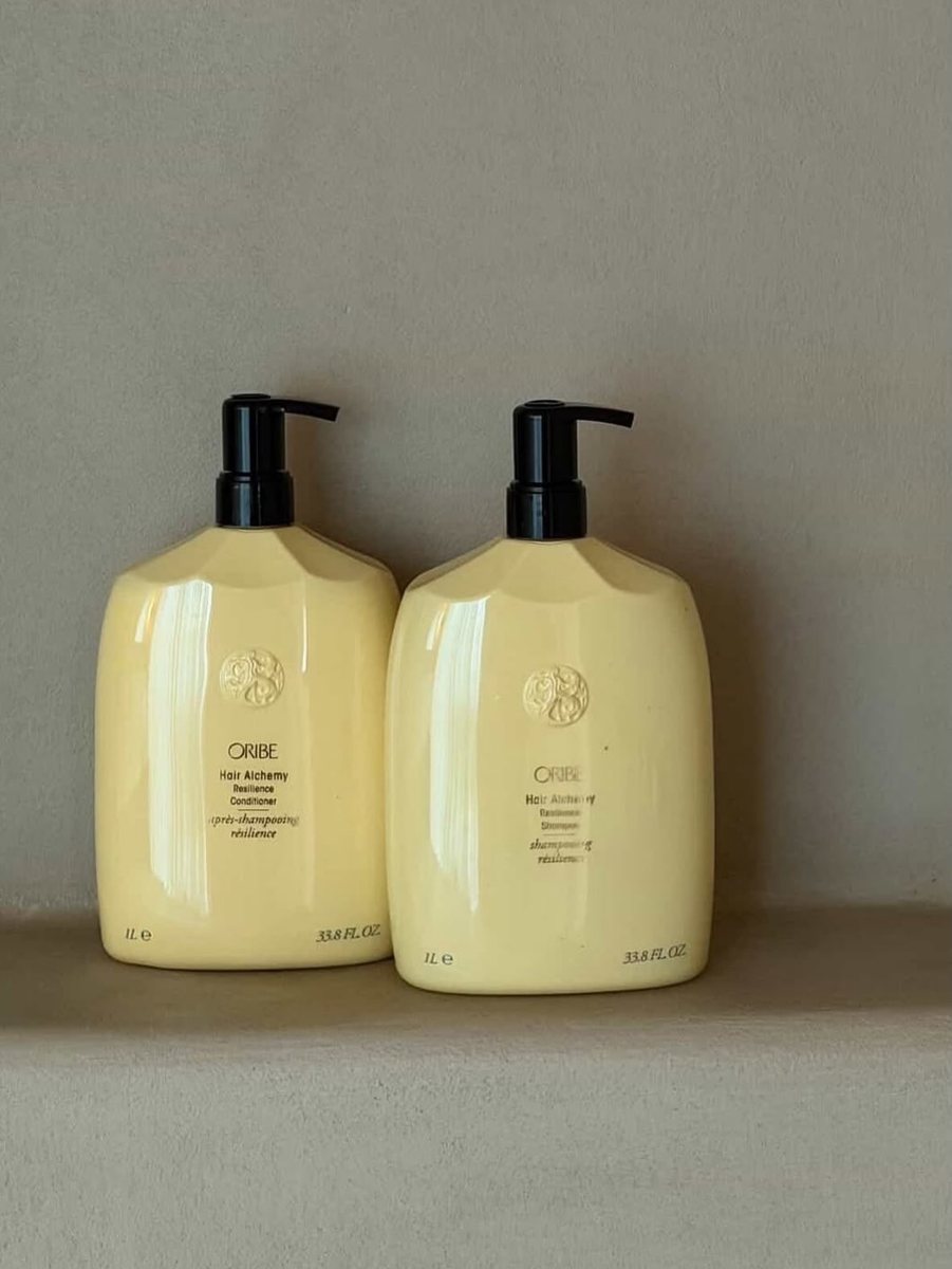 Dos botellas de champú Oribe sobre una repisa